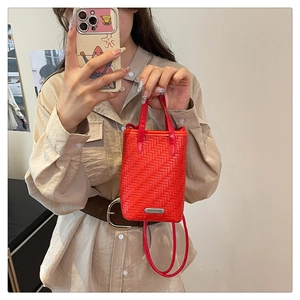 Détail du sac seau tissé rouge montrant la texture en V et la plaque en métal argenté