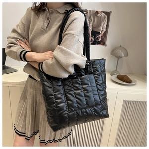 Détail d'un sac cabas noir en duvet matelassé avec une finition brillante moderne