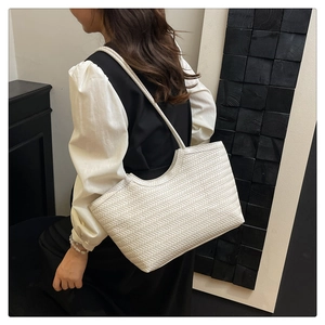 Close-up of cream woven tote bag showing detailed V-shape texture and long strap