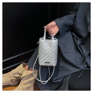 Close-up of silver woven crossbody bag with detailed herringbone texture and dual handles