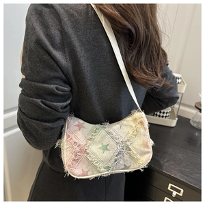 Detail of star pattern denim shoulder bag with frayed edges and colorful patchwork design