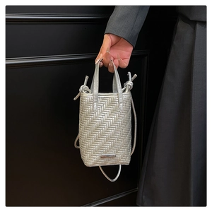Detailed close-up of a silver woven crossbody bag with metallic texture and logo plate