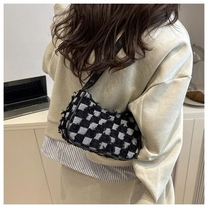 Close-up of stylish checkered tweed shoulder bag with fringed edges and leather strap