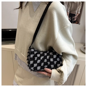 Detail of checkered denim bag showing frayed edges and leather strap on model