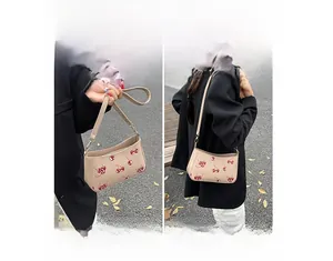 Detail view of beige hobo bag with red cherry print and adjustable shoulder strap style
