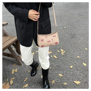Photo de rue d'un sac à bandoulière beige avec des motifs de cerises rouges