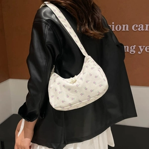 Corduroy underarm bag with purple floral pattern shown on shoulder with black jacket