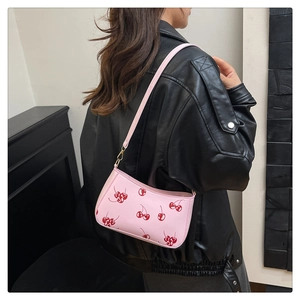 Close-up of pink cherry print shoulder bag with gold buckle on a black leather jacket