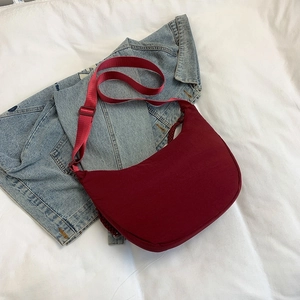 Minimalist burgundy nylon crescent shoulder bag on denim background for casual daily style