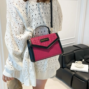 Rose red woven handbag with black trim and envelope flap shown on a fashion model