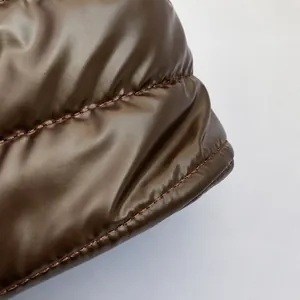 Macro shot of dark brown quilted puffer fabric with fine stitching and metallic gloss