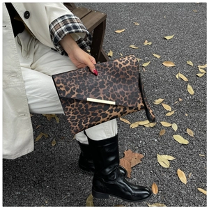 Detail of leopard print envelope clutch with gold metal trim and wrist strap accessory