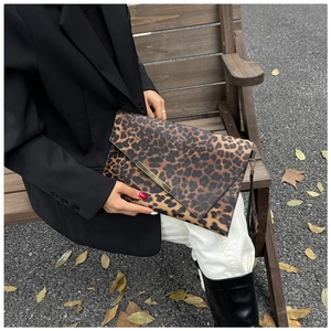 Détail de la pochette léopard avec barre en métal doré et dragonne noire élégante