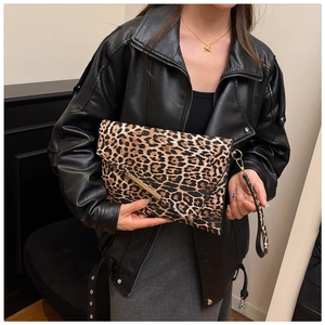 Leopard print clutch bag with gold metal trim held by a model in a black leather jacket