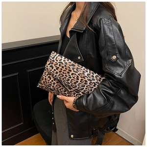 Detail of trendy leopard print envelope clutch bag held by a model in a leather jacket