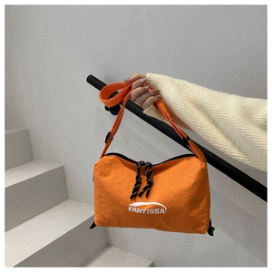 Détail d'un sac bandoulière en nylon orange vif avec logo imprimé et sangle réglable