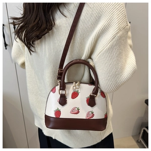 Détail du mini sac à main aux motifs fraises avec bandoulière en cuir sur un mannequin