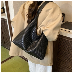 Dettaglio della trama intrecciata nera di una borsa hobo minimalista in interni casa