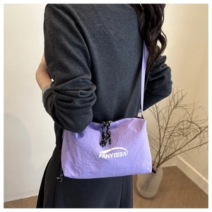 Detail of light purple nylon crossbody bag featuring textured fabric and brand logo