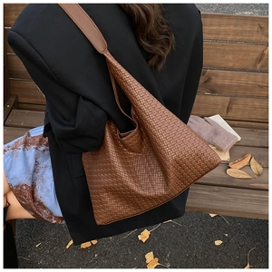 Close-up of brown woven hobo tote bag with detailed texture on a black blazer