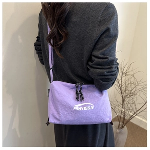 Detail of lavender nylon shoulder bag showing brand logo and textured zip puller