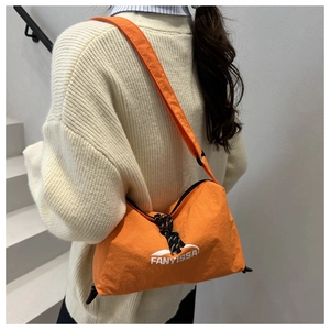 Vue détaillée du sac bandoulière orange en nylon léger porté par un mannequin au dos