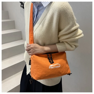 Détail d'un sac bandoulière en nylon orange vif avec cordon et logo imprimé blanc