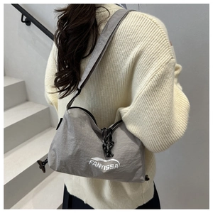 Détail d'un sac bandoulière gris en nylon avec cordon sur un pull beige doux