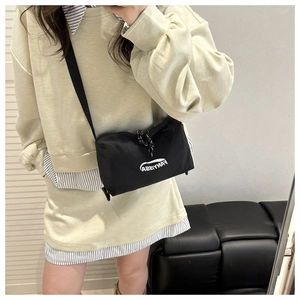 Detail of black nylon crossbody bag with white FANYISSA logo and woven zipper pull