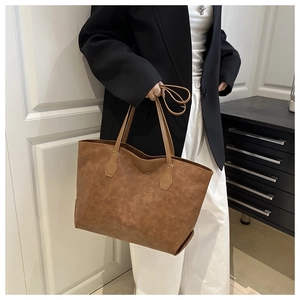 Detail of a large dark brown tote bag in retro oil leather worn over the shoulder
