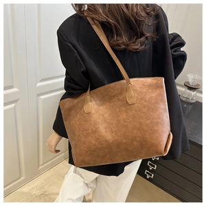 Brown leather tote bag with vintage marble texture worn by a model in a minimal setting