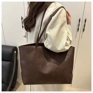 Model wearing dark brown vintage leather tote bag in a minimalist home setting