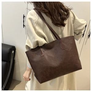 Dark brown large capacity tote bag shown from side back view on person in a home setting