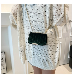 Close-up of deep green velvet crossbody bag featuring quilted texture and gold chain