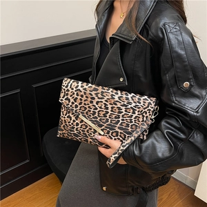 Stylish leopard print crossbody bag with gold chain and wrist strap held by model