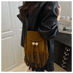 Detail of a brown faux suede crossbody bag with long tassels and wooden bead drawstring