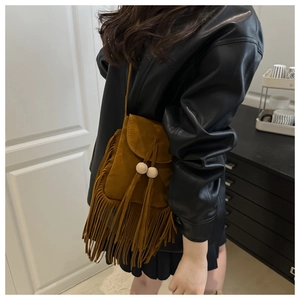 Détail d'un sac bandoulière en daim marron avec franges et perles en bois porté