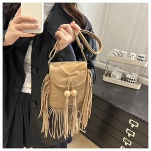 Detail of bohemian khaki faux suede crossbody bag featuring long fringes and wooden beads
