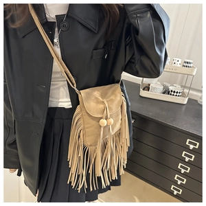 Detail of khaki suede crossbody bag featuring long fringe tassels and wood bead accents