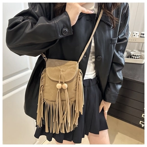 Detail of khaki suede crossbody bag featuring bohemian fringe and wooden bead accents