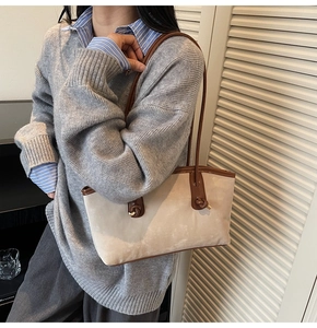 Detail of a beige suede tote bag featuring contrasting dark brown leather shoulder straps