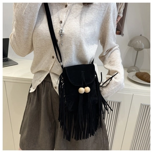 Detail view of black faux suede crossbody bag with long fringes and wooden beads