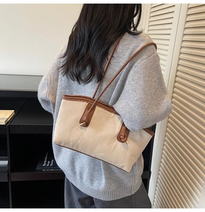 Detail of a beige tote bag with brown straps and 'FASHION & BAGS' text on shoulder