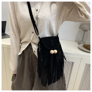 Détail du sac bandoulière en daim noir avec franges rétro et perles en bois sur le rabat