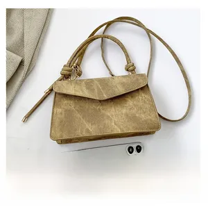 Top view of a vintage khaki crossbody bag with a knotted handle and phone for scale