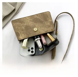Detail view of brown vintage crossbody bag interior showing phone and makeup storage