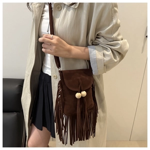 Detail of bohemian dark brown suede crossbody bag with long tassels and wooden beads