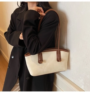 Close-up of the beige leather tote bag featuring a knotted strap and fashion logo detail