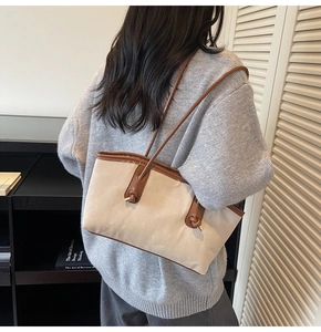 Detail of beige tote bag with brown straps showing fashion text and gold hardware