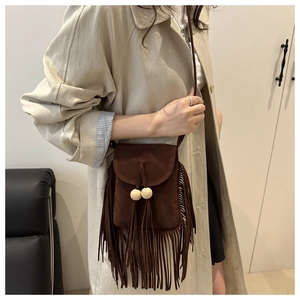 Close-up of coffee brown suede crossbody bag featuring long fringe and wooden beads